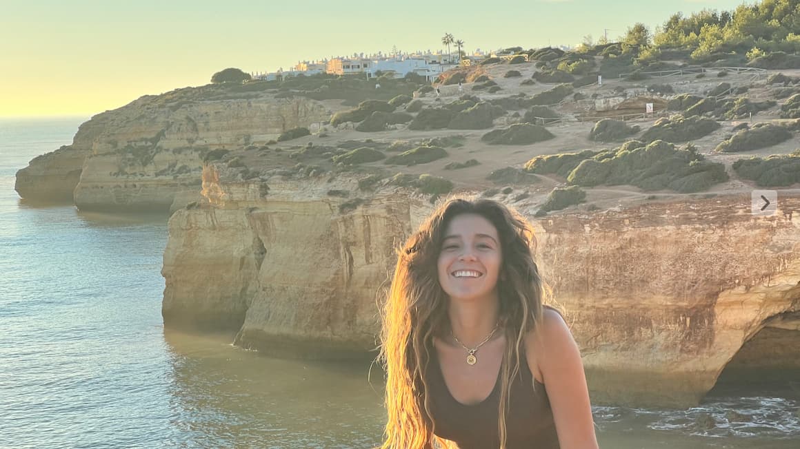 a girl smiling in front of scenic cliffs and the ocean of lagos,portugal