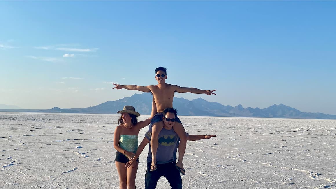 three friends smiling a Bonneville salt flats  in Utah