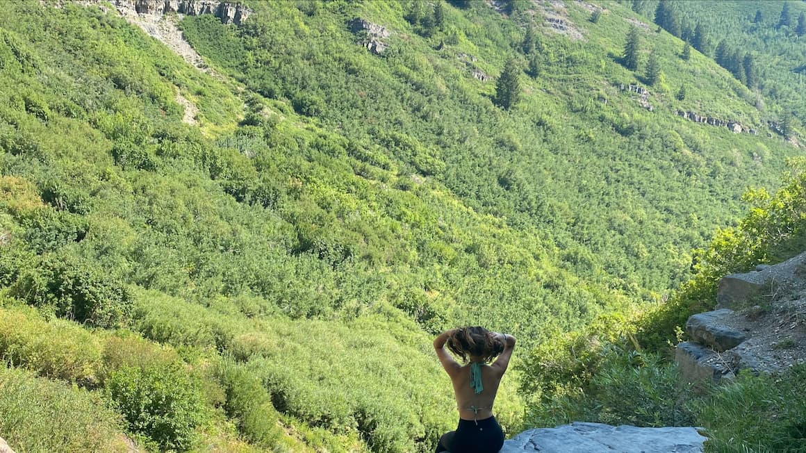 a girl sitting on a rock looking at the trees in the mountains in park city, utah 