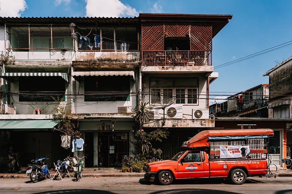 A red taxi sitting in front of typical houses in Chiang Mai, Thailand