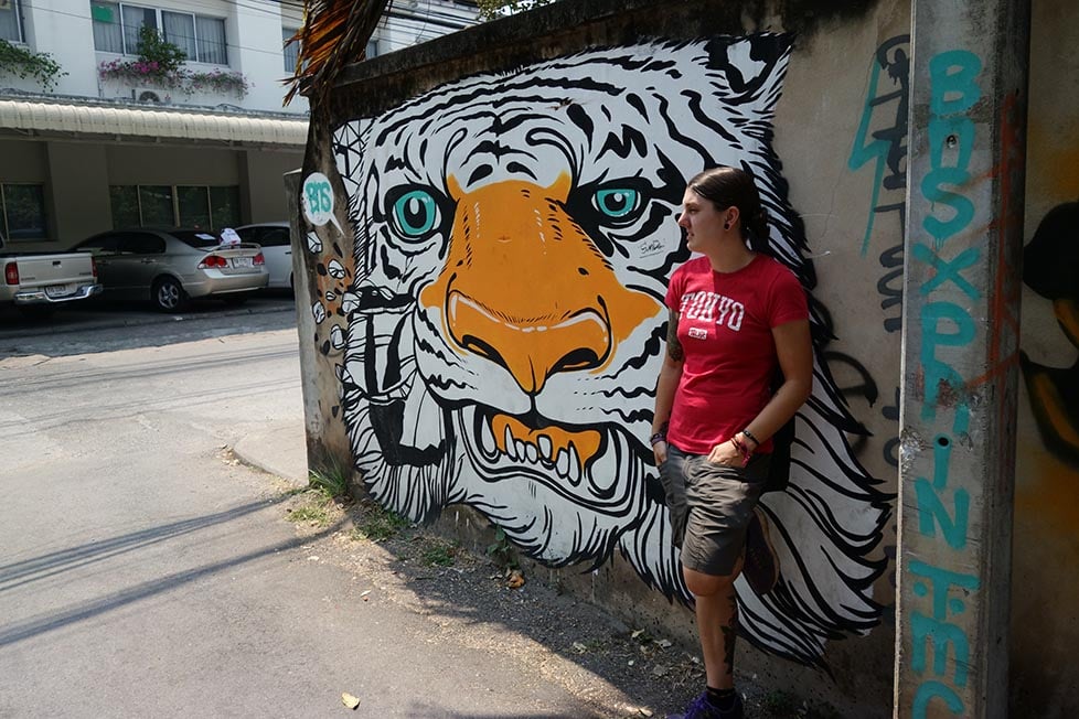 A person leaning against a wall with a tiger mural in Chiang Mai, Thailand