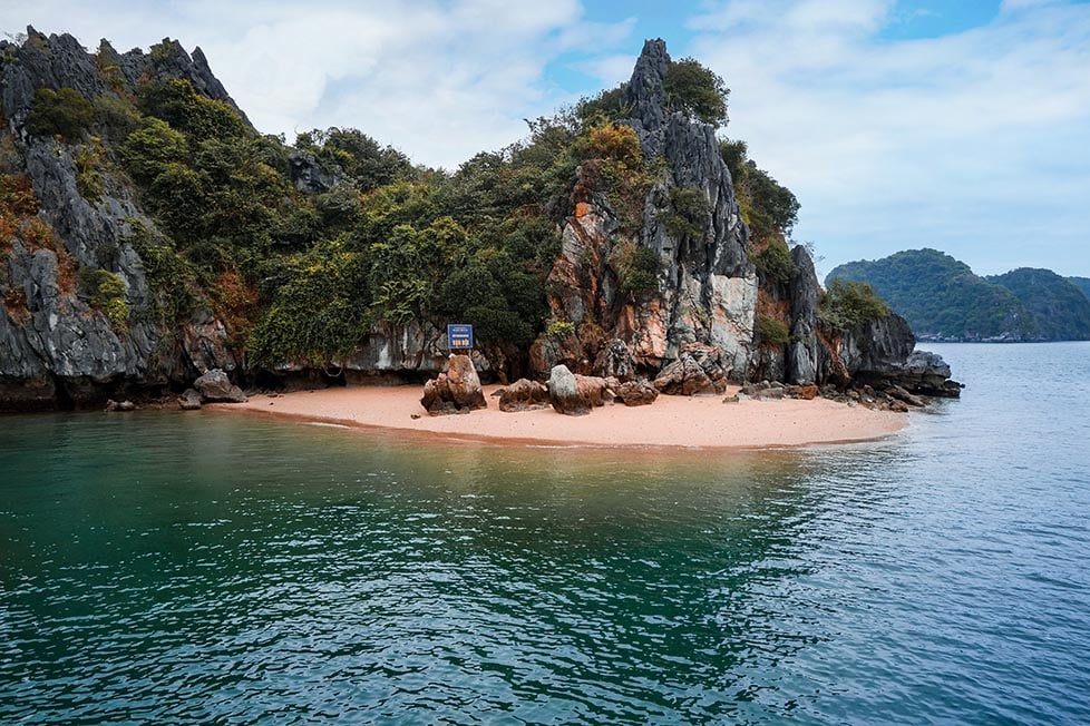A beach surrounding a rocky limestone peak in Ha Long bay, Vietnam