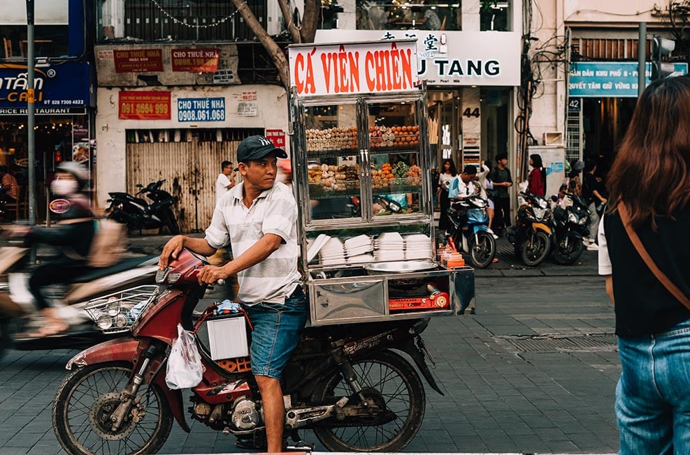 A man on a motorbike selling street food on a bust street in Vietnam