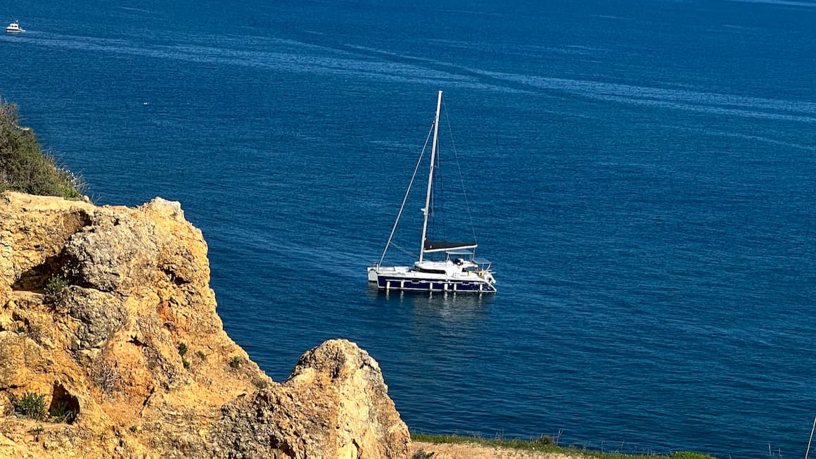 a sail boat in the middle of the blue ocean 