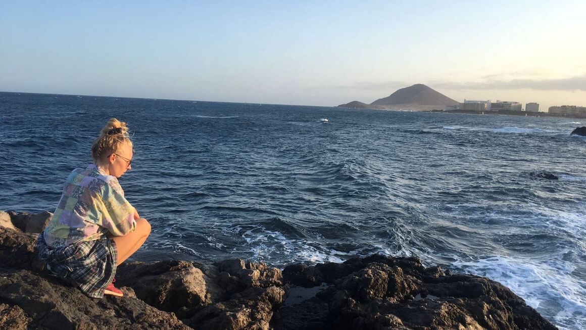 Girl sitting on the rocks near the ocean