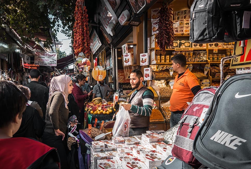 A street market vendor in Istanbul, Turkey is selling spices to a local woman on a very crowded street.