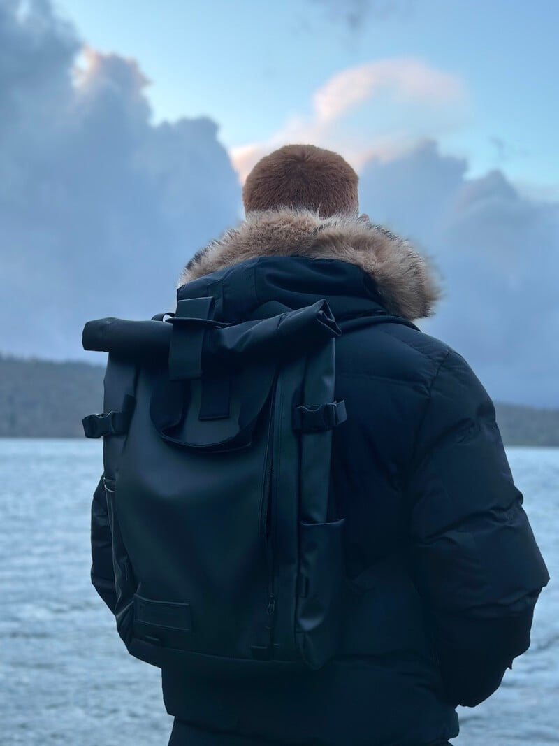men wearing Wandrd PRVKE 31l backpack gazing across a scenic lake landscape