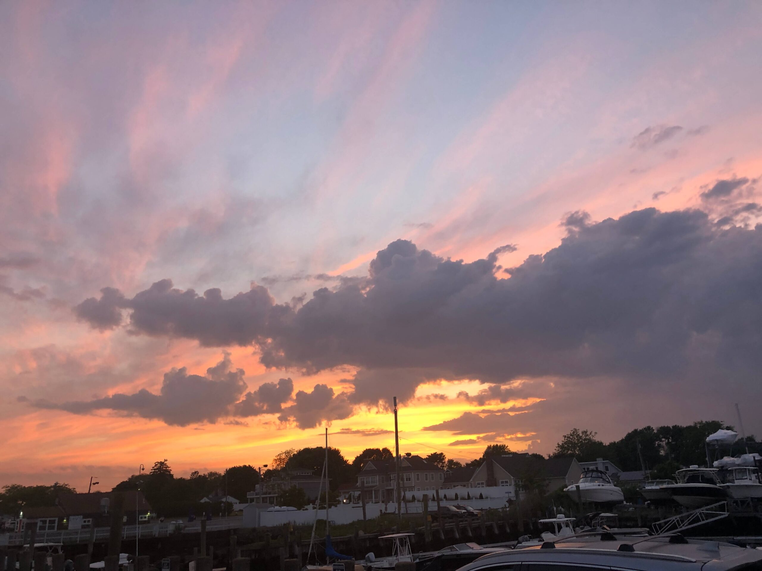 an incredible orange and pink sunset as seen at a marina full of boats on water in connecticut in new england usa