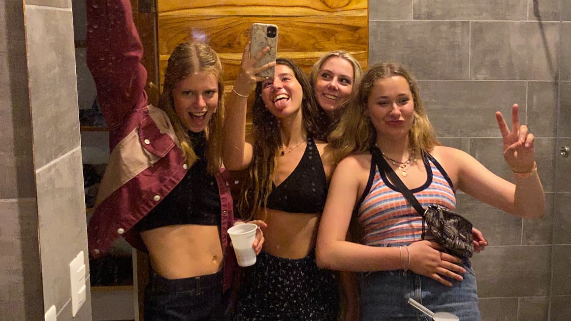 a group picture being taken in the mirror of a hostel in costa rica