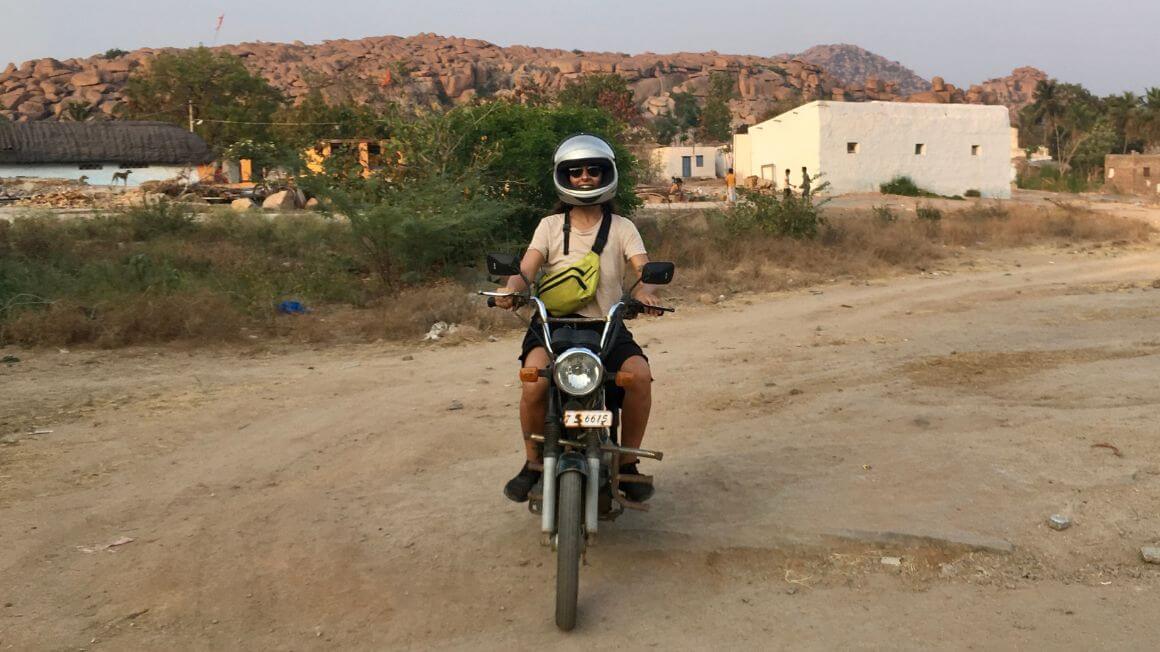 backpacker wearing a helmet smiles on a rental bike ready for adventure