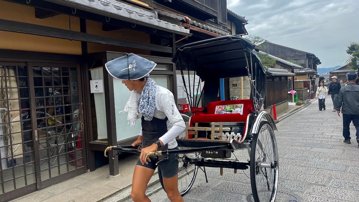 Guy pulls carriage through streets of Tokyo.