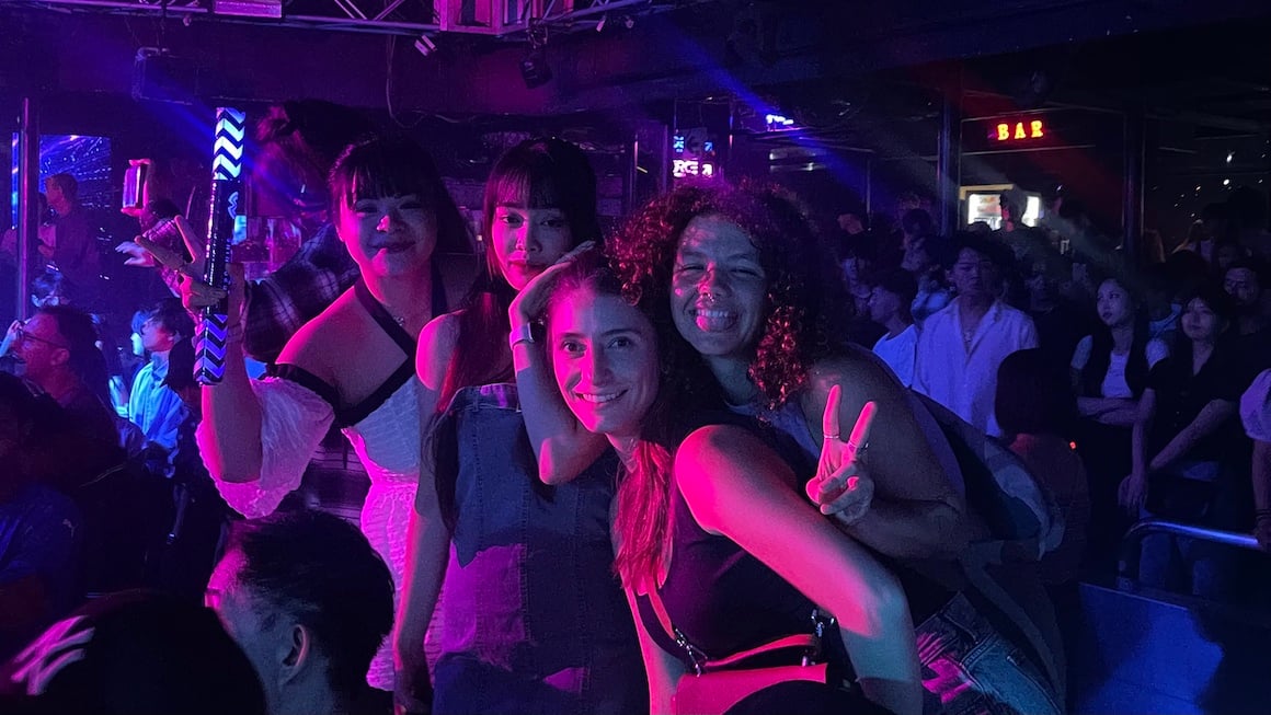 A group of friends smiles for a photo in a Tokyo club.