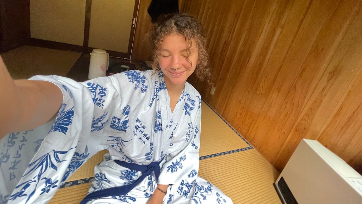 A girl dressed in a traditional Japanese kimono smiles for a photo.