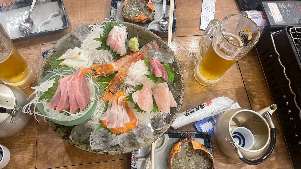 A photo of a classic Japanese meal, sake, beer and sashimi.