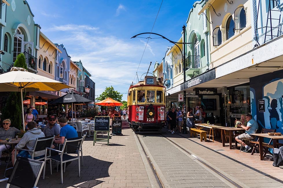 A tram rolls down a street with old pastel coloured buildings in Christchurch, New Zealand