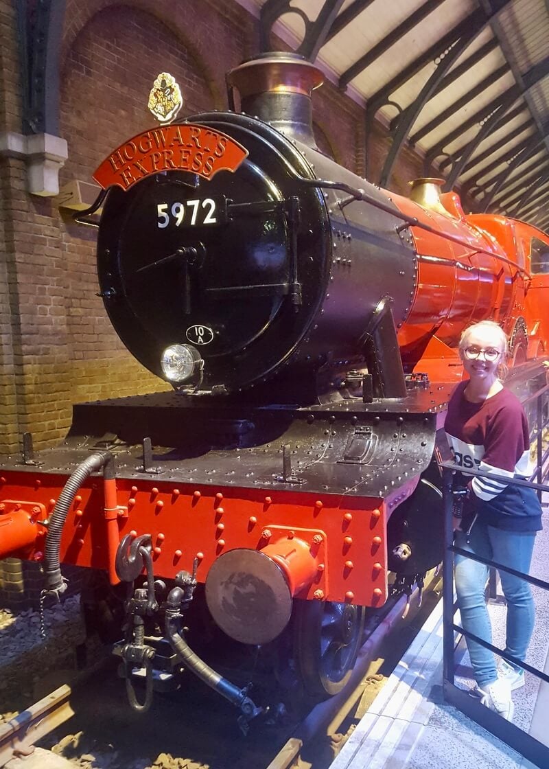 Woman stood smiling next to Hogwarts Express train