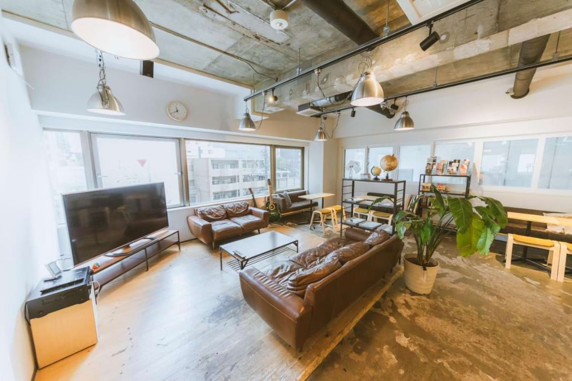 A living room with a brown couch, a white coffee table, and a flat-screen tv in The Stay Sapporo