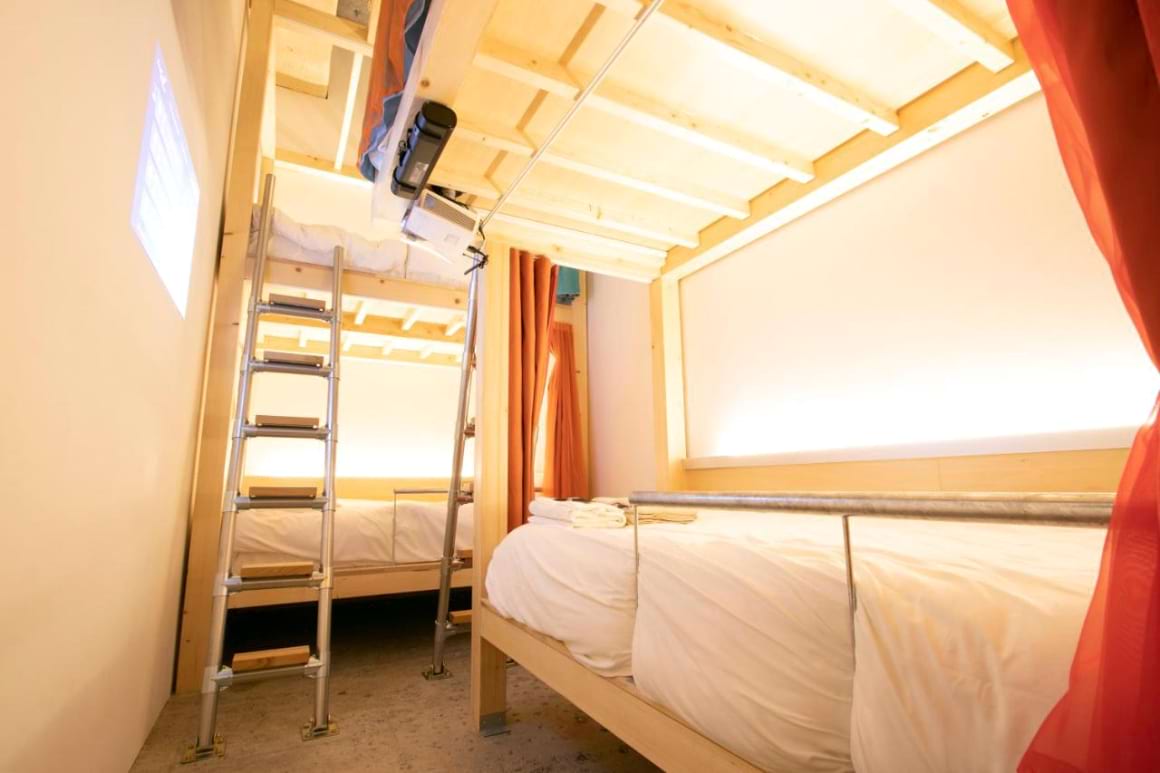 A warmly illuminated dorm room at Theatel Sapporo, adorned with a bunk bed and ladder