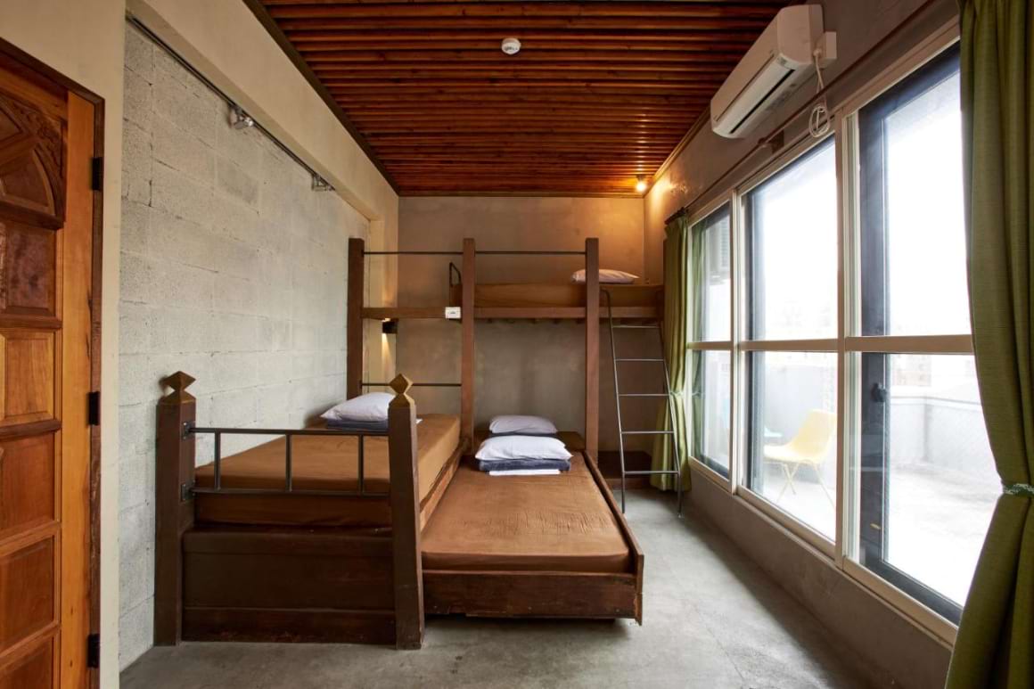 A simple room with a bunk bed positioned in front of a large window in Unstapped Hostel