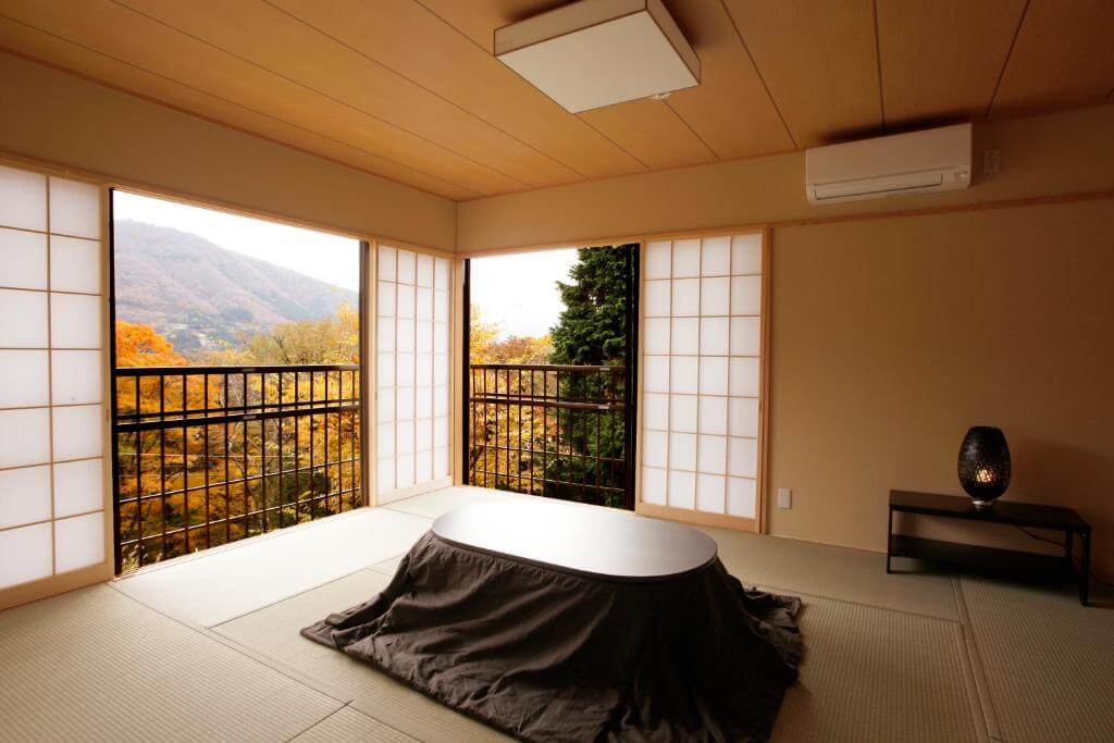 A simple room interior with a tatami mat floor and a nature view of Hakone 