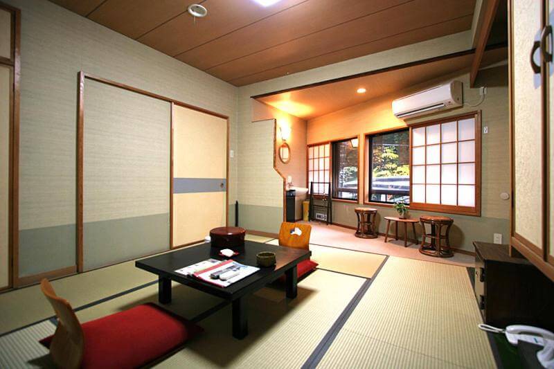 A spacious Hakone Ryokan with a low wooden table and four black chairs. 
