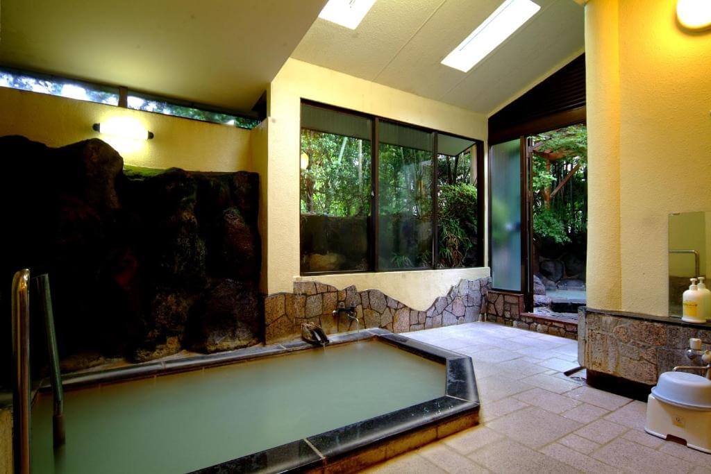 A bathroom with a large bathtub filled with water at Mitake