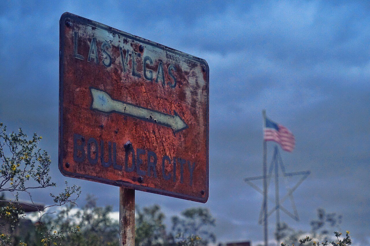 A rusty Las Vegas street sign with red paint arrow pointing right.