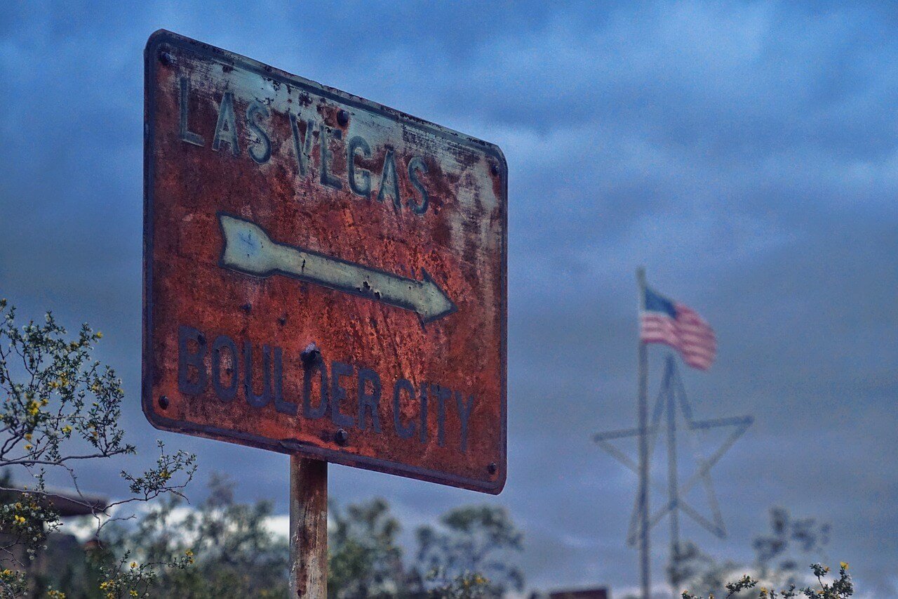 A rusty Las Vegas street sign with red paint arrow pointing right. 