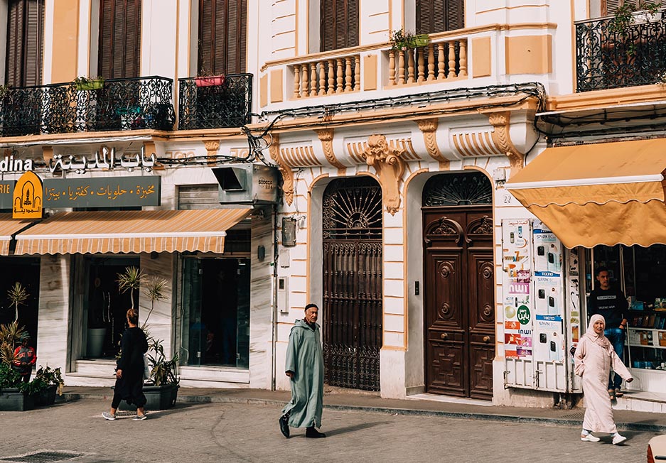 Local people walking past a colonial era building in Tangier, Morocco.