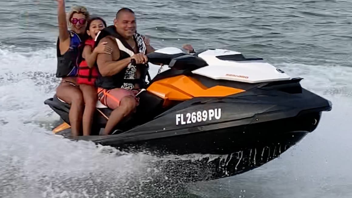 A family of three people on an orange jet ski in Miami Florida smiling
