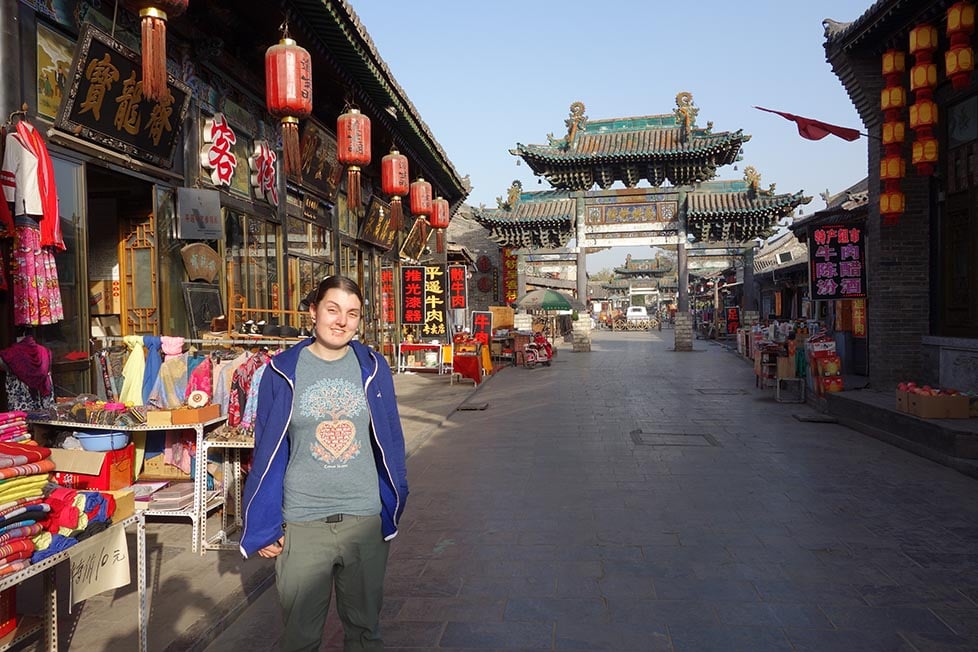 Nic standing on a street with a traditional Chinese gate behind them in Pingyao, China.