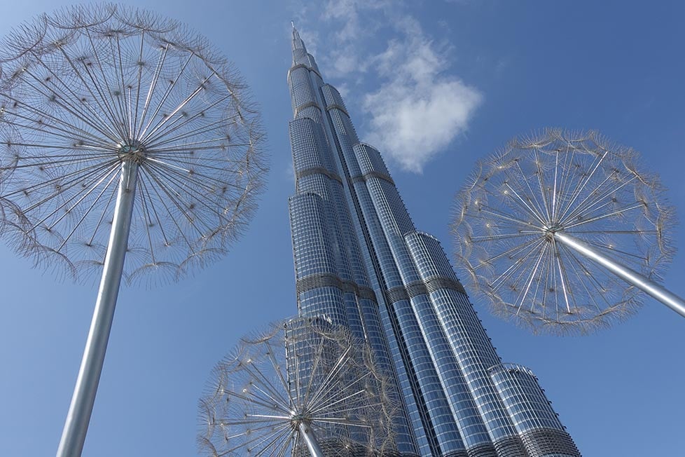 Looking up at the Burj Khalifa from the ground with metal dandelion sculptures in the foreground.
