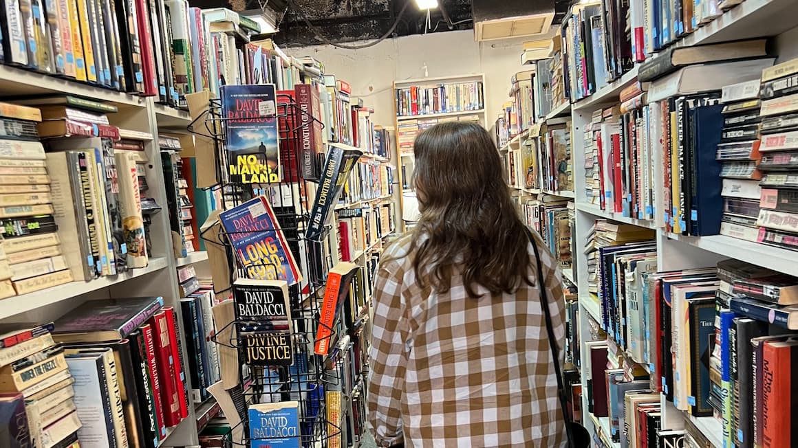 a girl walking through a bookstore looking for a book 