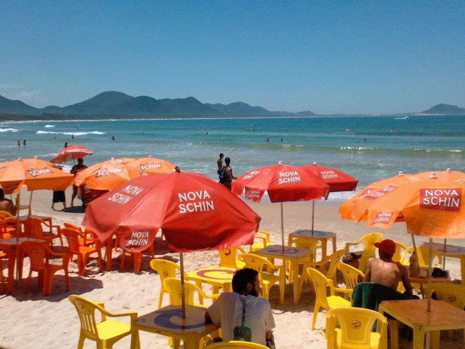 Beach in the Canasvieiras area with umbrellas, crystal clear waters and hills in the background.