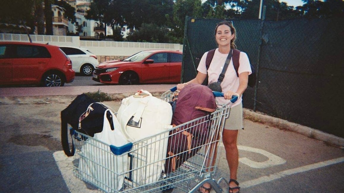 danielle hitchhiking with a trolley full of backpacks hoping to be picked up