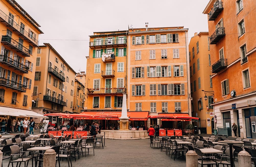 A square with restaurants and cafes surrounded by old buildings in Nice, France.
