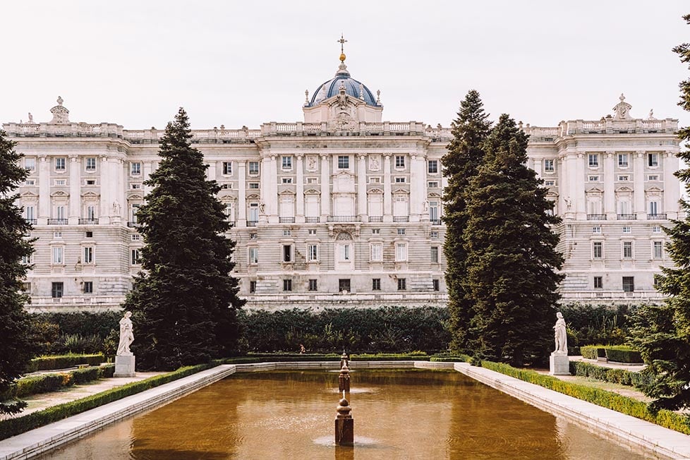 The side of the Royal Palace in Madrid, Spain with gardens and a pond in the foreground