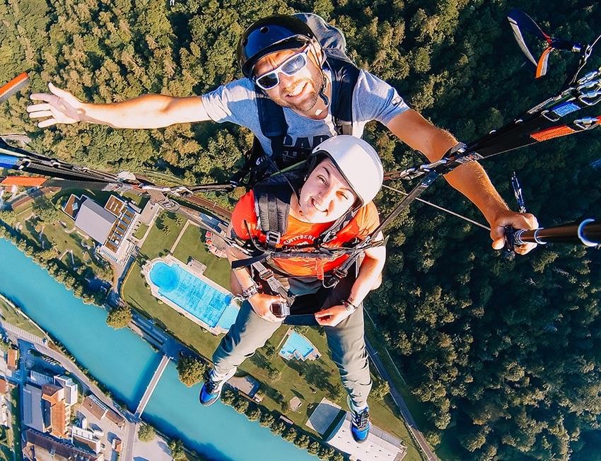 Nic paragliding over Interlaken, Switzerland with the river and swimming pools of the town below.