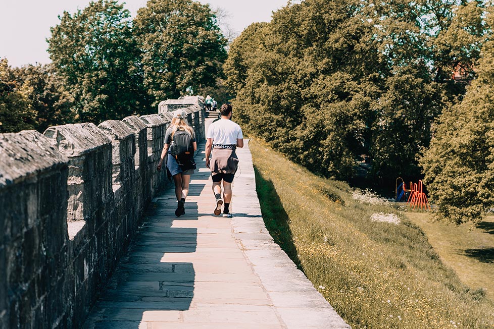 Two people walking along the old walls of York, England, United Kingdom