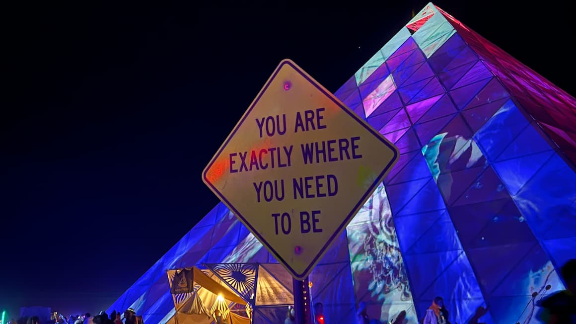 a sign that says "you are exactly where you need to be" that is in front of a pyramid at the burning man festival in nevada, usa