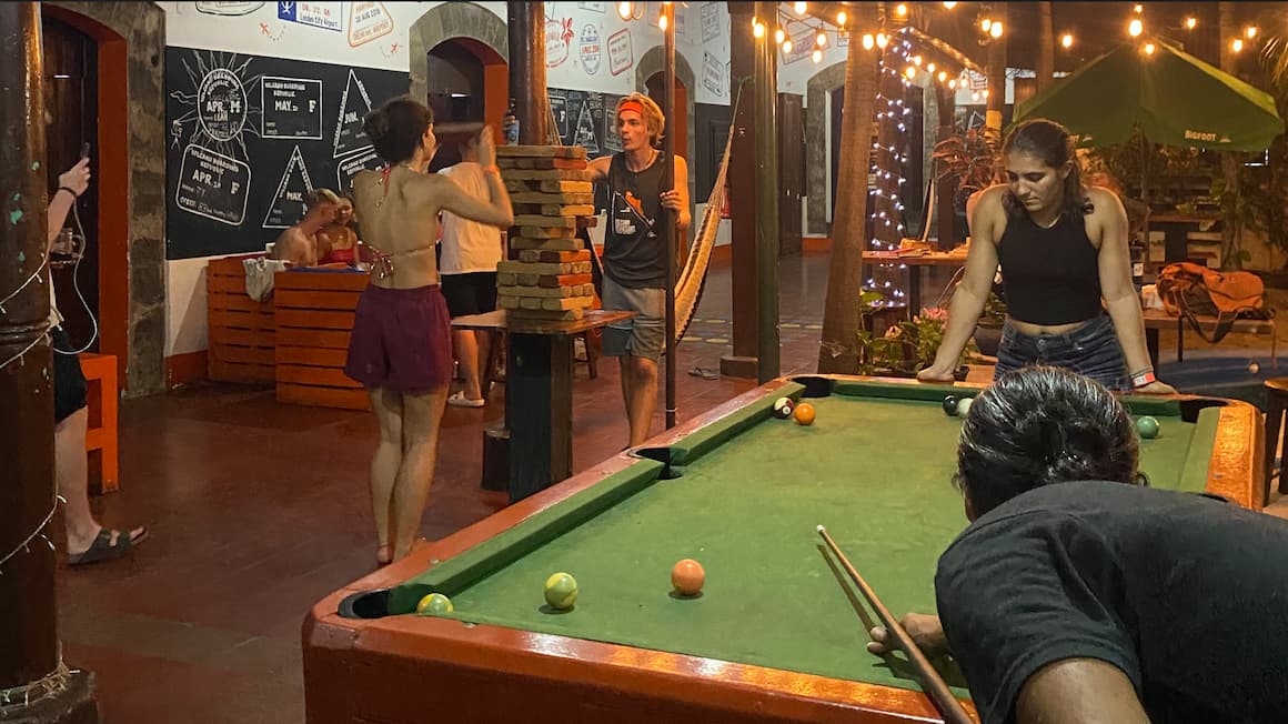 a group of friends playing jenga and playing pool on a pool table at a hostel in Nicaragua
