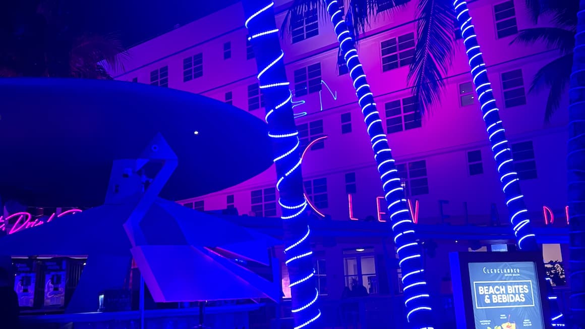 south beach, Miami, florida, at night time with purple lights wrapped around the palm trees