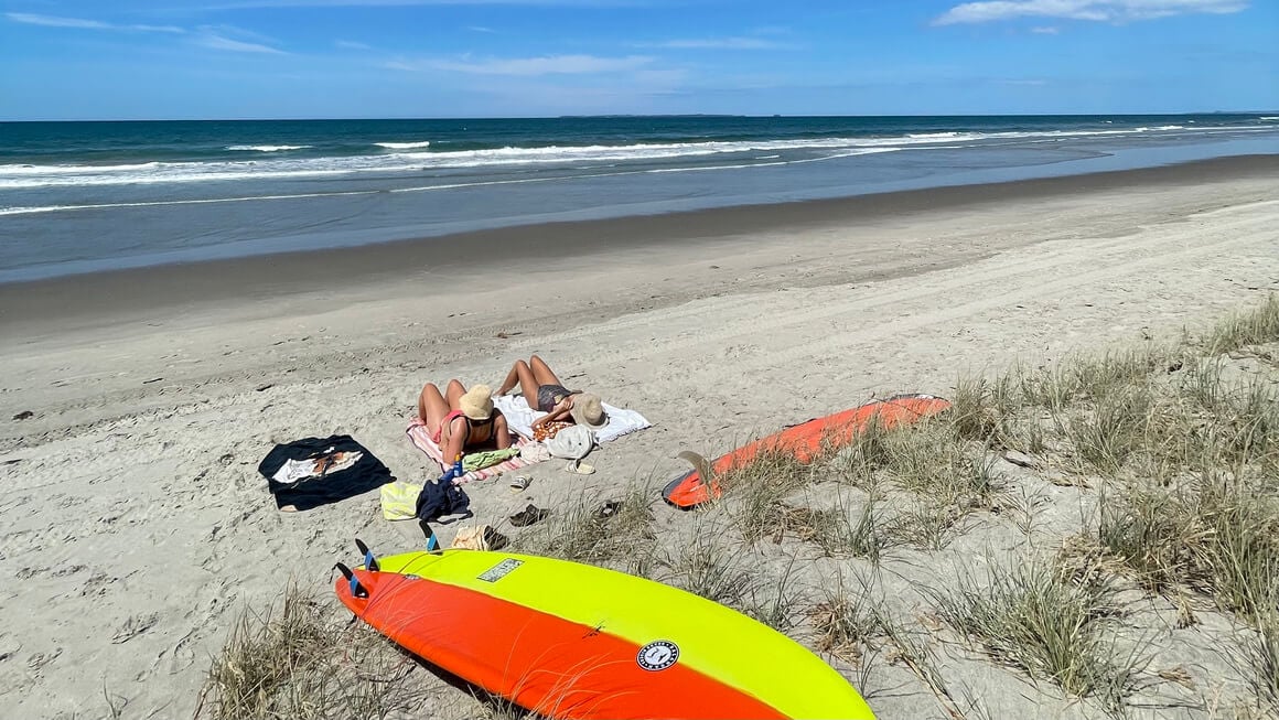 friends with surf boards relaxing at east coast beach in New Zealand