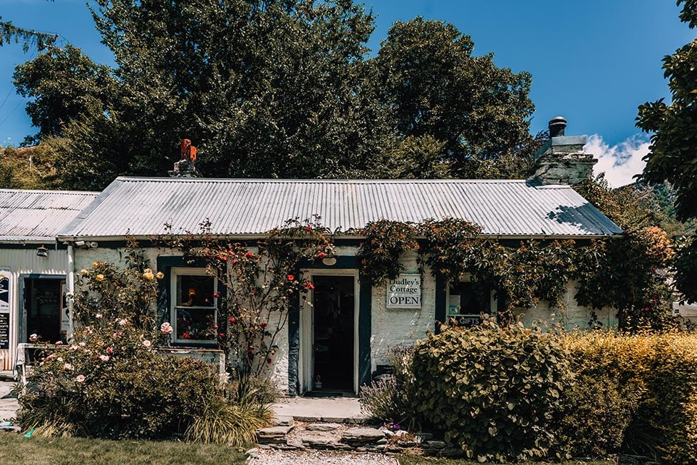 An old cottage covered in rose bushes and a tin roof near Queenstown, New Zealand.