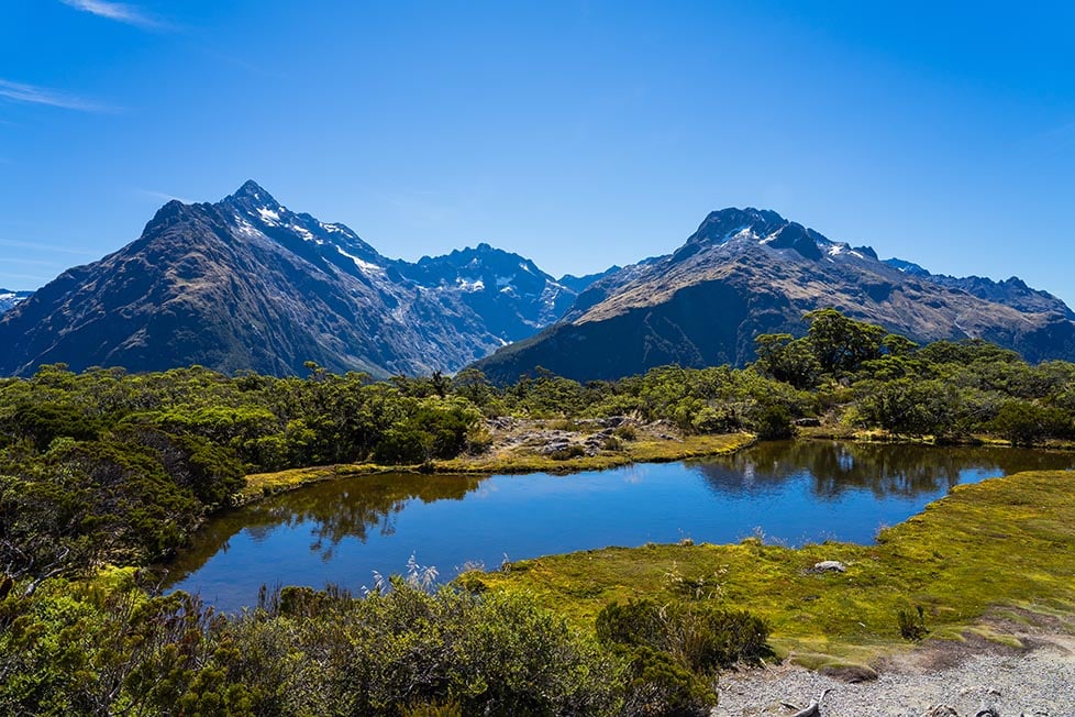 Looking out over the glacier covered mountains with a small lake in the foreground outside of Queenstown, New Zealand.