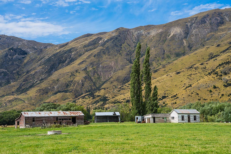 Farm buildings with towering mountains behind near Queenstown, New Zealand