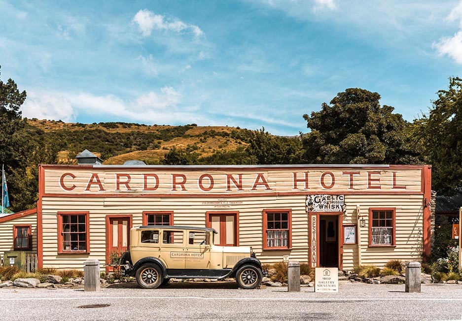 The famous old wooden Cardrona Hotel and an old 1920's car in front of it in Queenstown, New Zealand. Wes Anderson style.