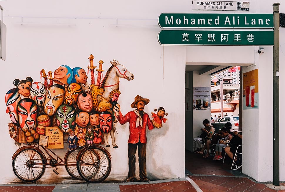 Street art showing a man selling ornate masks in Singapore.