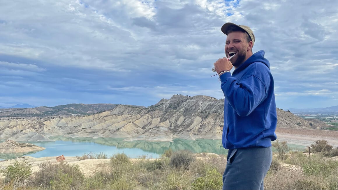 man brushing teeth in the mountains whilst on a van trip