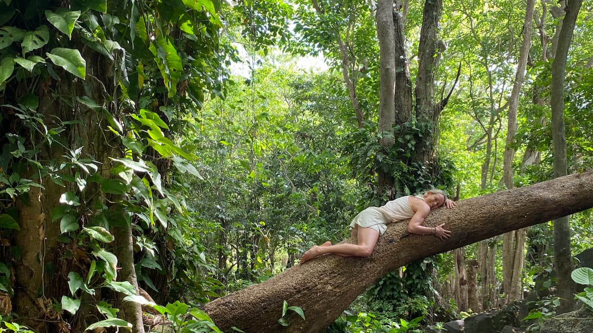 a girl laying down hugging a slanted tree in the jungle of ometepe island, Nicaragua 